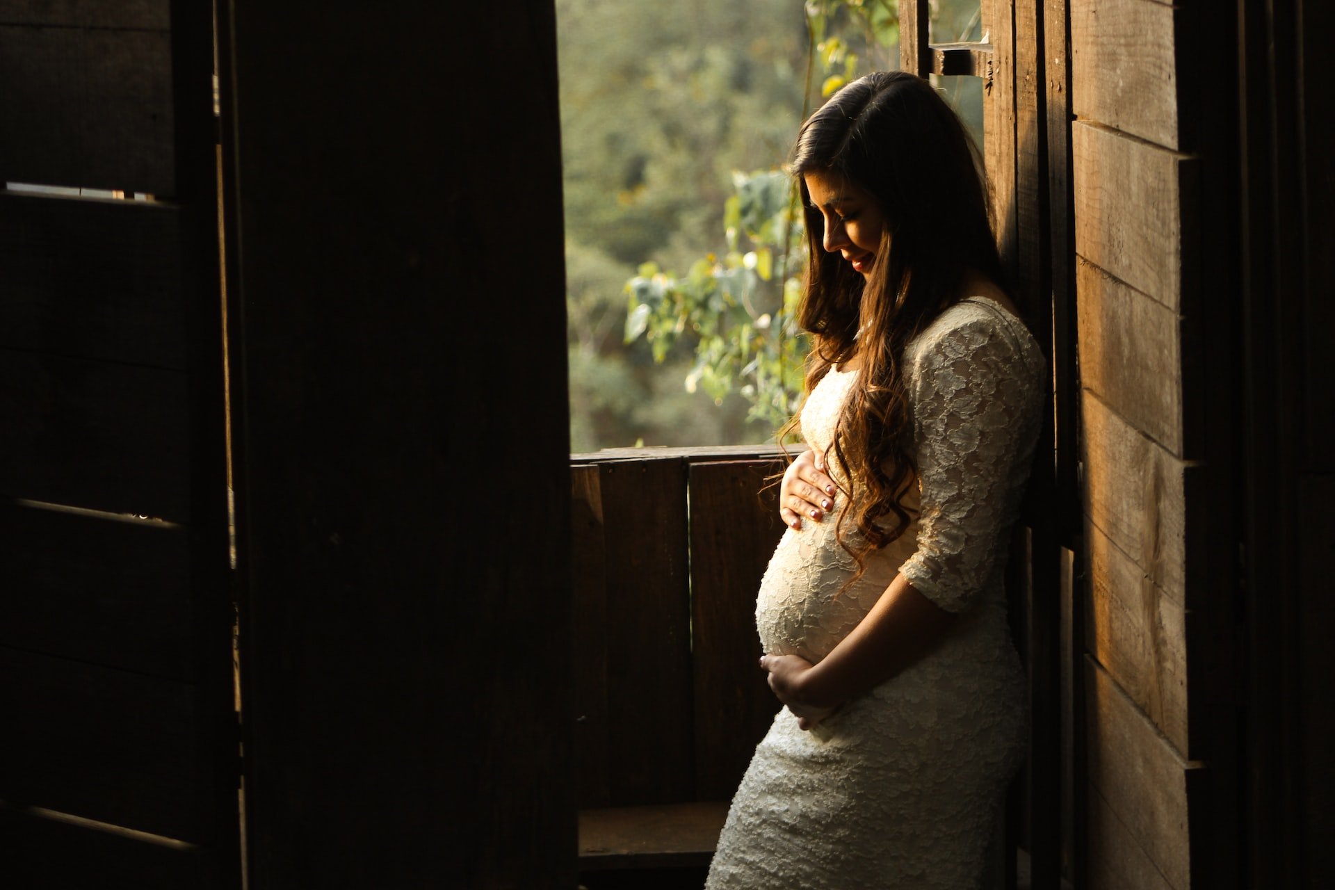 mujer embarazada mirando sobre la ventana
